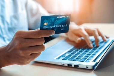 Genç adam, laptop bilgisayar başvurusu ya da web sitesinde online alışveriş yapmak için kredi kartı kullanıyor. E-ticaret ve online alışveriş konsepti. uds