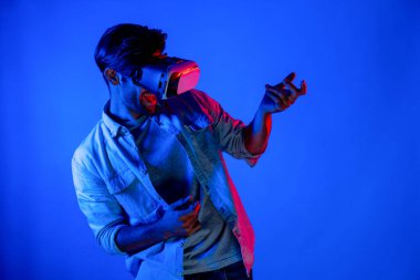 Beyaz adam hareket ediyor, gitar çalıyor ve arka planda ışık yansıması olan bir VR cam takıyor. Oyuncu metaevren ya da sanal gerçeklik programına teknolojik yenilikler kullanarak girer. Sapma.