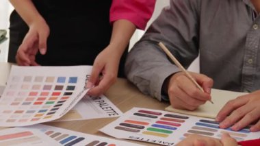 Grafik tasarımı için beyin fırtınası yapan ve renk seçimi yapan tasarımcı ekibinin yavaş çekim çekimi veya tasarım bürosunda krom danışmanlığı için danışmanlık isteyen bir müşteri. Değiştirilmiş