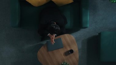 Stres atmak için kanepede yatarken dizüstü bilgisayarda çalışan zeki iş adamının yukarıdan görünüşü. Stresli işçiler koltukta uyurken iş planı ya da pazarlama stratejisini düşünüyorlar. Müdürlük.