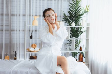 Kaplıca salonunun sakin, modern gün ışığı atmosferi, kadın müşteri poz veriyor ve yüz maskesi ile gençleştiriyor. Yüz bakımı ve güzellik kozmetolojisi prosedürü. Sessiz.