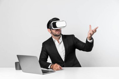 Bilgisayarla masada otururken ve VR gözlüğü takarken veri analizine bakan yetenekli bir iş adamı. Proje yöneticisi sanal gerçeklik sistemini kullanarak ya da metaevrende bağlantı kurarak çalışıyor. Sapma.