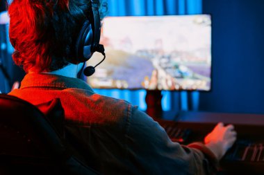 Genç oyun flamasının sunucu kanalı, takım oyuncusu, dijital neon odasında mikrofonlu kulaklık takarak bilgisayar ekranında çoklu oyuncuyla savaş oyunu oynuyor. Toplayıcı.