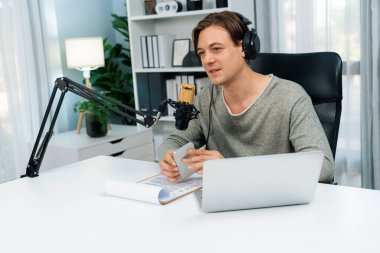 Sunucu kanalı, gülümseyen akıllı yayıncı kaydı, senaryosu ve akıllı telefonuyla sosyal medyada sohbet programı, kulaklık takarak modern ev stüdyosundaki video flamalarını kaydediyor. Bireysel.