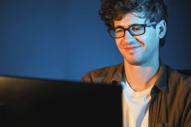 Neon Light Modern Ofis 'te yaratıcı bir başlangıç projesi için bilgisayara odaklanan gülümseyen genç iş adamı. Düşünüyorum da, pazarlama ağı yaratıcıdan pazar kanalı tasarım konseptine çevrimiçi planlama. Toplayıcı.