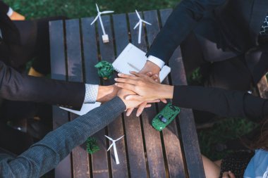 İş adamları takım çalışması ve birlik olarak el ele tutuşuyor, açık hava iş toplantısı masası. Çevre dostu uygulamalar ve daha yeşil bir çevre için kurumsal sosyal sorumlulukta işbirliği. Döngü