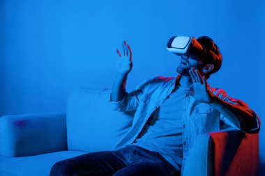 Kanepede otururken VR gözlüğü takıp korku filmi izleyen korkmuş bir insan. Kafkasyalı bir adam sanal gerçeklik simülasyonu kullanarak korku oyunları oynuyor. Sapma.