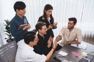 Çeşitli ofis çalışanları stratejik iş pazarlama toplantısı üzerine anlaşma yaptıktan sonra el sıkışıyor. Takım çalışması ve olumlu tutum verimli ve destekleyici bir iş yeri yaratır. Tedbirli