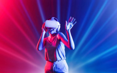 Zeki bir kadın, metaevreni birbirine bağlayan VR kulaklık takan neon ışıklarla çevrili duruyor. Gelecekteki siber uzay topluluğu teknolojisi. Zarif bir kadın dans etmekten, dans etmekten ve şarkı söylemekten hoşlanır. Halüsinasyon.