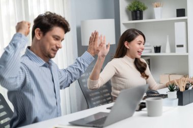 Gülümseyen mutlu iş arkadaşları beşlik çakıyor aynı zamanda yaratıcı proje planını yumrukluyor ve sabahları modern ofiste gündelik işlerde en yüksek kârı elde ediyorlar. Varsayım.