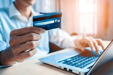 Genç adam, laptop bilgisayar başvurusu ya da web sitesinde online alışveriş yapmak için kredi kartı kullanıyor. E-ticaret ve online alışveriş konsepti. uds