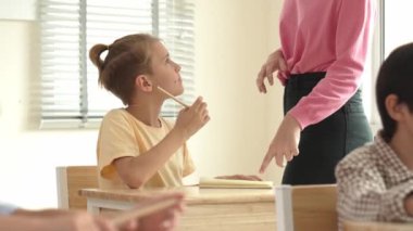 Beyaz bir çocuk ödevlerini yaparken ve açıklama dinlerken güzel bir öğretmen sınavı açıklıyor. Sınıfta not alırken ya da kağıda cevap yazarken öğretmenine bakan sevimli bir çocuk. Pedagoji.