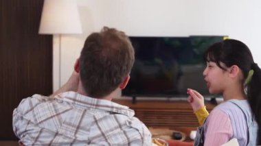Grandfather and granddaughter eat french fries watch interesting entertainment on TV. Senior use technology communicate with young generation cross generation gap strengthen family bond. Divergence.