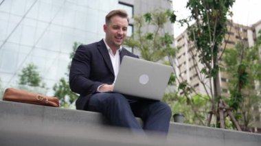 Dizüstü bilgisayarı üzerinde çalışan ve başarılı bir projeyi kutlayan ya da yeşil kentlerdeki satışları artıran bir yönetici. Profesyonel işadamı bankta otururken bilgisayar kullanarak analiz verilerine bakıyor. Urbane.