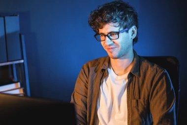 Neon Light Modern Ofis 'te yaratıcı bir başlangıç projesi için bilgisayara odaklanan gülümseyen genç iş adamı. Düşünüyorum da, pazarlama ağı yaratıcıdan pazar kanalı tasarım konseptine çevrimiçi planlama. Toplayıcı.