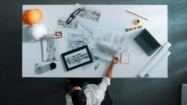 Yetenekli inşaat mühendisinin ev modeline bakarken oturup fikir yazması. Mimarın ya da tasarımcının yaratıcı bina inşaatını planlama ve düşünme havadan görünüşü. Hizalama.