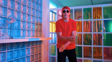 Komik break dansçı kameraya bakarken hiphop 'a doğru serbest adım atıyor. Çılgın mutlu hipster dans edip sokak dansı yaparken Led ışığında günlük kıyafet ve güneş gözlüğü takıyor. Mutluluk.