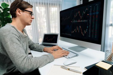 Bilgisayar ve dizüstü bilgisayarı kullanarak, çalışma masasındaki dinamik artırılmış borsa grafiğinin en yüksek kar değerini araştıran bir tüccar, modern ofisteki ekrandaki döviz kuru değerini analiz ediyor. Bireysel.