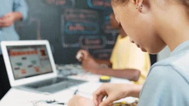 Öğretmenler kodlama sistemini öğretirken, farklı akademik öğrenciler STEM teknoloji sınıfında ana tahtayı dizüstü bilgisayar programlama programlama veya mühendislik kodu ile düzeltiyorlar. Öğretim