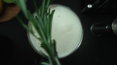 Barmen manzarası turuncu ve biberiyeli modern barla kokteyl hazırlıyor. Profesyonel barmen elleri, kan portakallı negroni ile siyah arka planda Rose Mary ile süslenmiş. Ağır çekim. Geliştirilebilir.