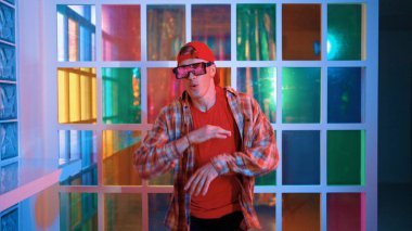 Komik break dansçı kameraya bakarken hiphop 'a doğru serbest adım atıyor. Çılgın mutlu hipster dans edip sokak dansı yaparken Led ışığında günlük kıyafet ve güneş gözlüğü takıyor. Mutluluk.