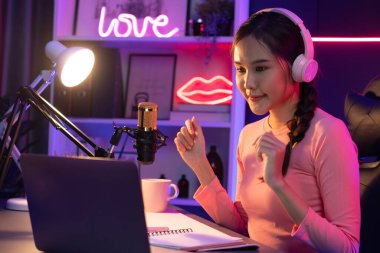 Geceleri podcast 'te olumlu konuşmalar yapan, pembe neon ışıklı modern stüdyoda sunum için dizüstü bilgisayar kullanan, gülümseyen, genç, güzel Asyalı bir etkileyiciydi. Taktik.