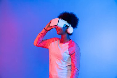 Profil, VR gözlük takan genç ve güzel Afrikalıların mavi ve pembe neon ışıklı arkaplanda izole olduğunu düşünüyor. Teknoloji ve dijital yenilik 3 boyutlu hologram gramında. Entrika.