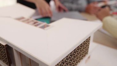 Mimari ekipman kullanarak yavaş çekim ev tasarımcısı bir plan çizerken, iç mimari tasarımcı da müşterilerin talebine göre renk örneklerinden uygun renkler seçiyor. Değiştirilmiş