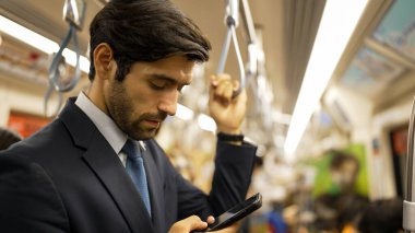 Trende insanlarla çevrili dururken telefona bakan profesyonel bir iş adamı. Kafkas proje yöneticisi e-postaları kontrol ediyor, arka planı bulanık pazarlama stratejisi planlıyor. Sevinçli..