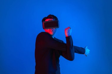 Zeki sporcu VR giyip tüm vücudunu mavi neon ışıklı arka plan üzerinde gererek dijital fütüristik teknoloji sanal gerçekliğini egzersiz konseptine bağlıyor. Entrika.