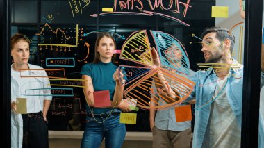 Yetenekli erkek lider, istatistik grafiğini uzman yatırımcılara açıklıyor. Akıllı iş adamı sunar, finans planlarını gece ofisindeki cam duvardaki yatırımcılara gösterir. İş konsepti. İzleme