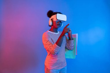 Canlı dijital fütüristik teknoloji meta metasında hologram uygulaması güzellik bezi ürünü üzerinde alışveriş poşeti tutarken İnternet üzerinden alışveriş yapan genç Afrikalıların keyfini çıkarın. Entrika.