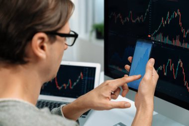 Akıllı borsa yatırımcıları ekranda akıllı telefon ile piyasa borsasını işaret ederek dizüstü bilgisayarın yanı sıra en yüksek dinamik yatırım oranını göstererek, modern işyerindeki veri planlamasına odaklanıyorlar. Bireysel.