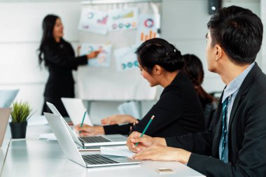 Uluslararası iş konferansında grup toplantı odasının önünde duran iş kadınının sunumunu dinleyen Asyalı işadamları. Çok kültürlü kurumsal strateji kavramı. uds