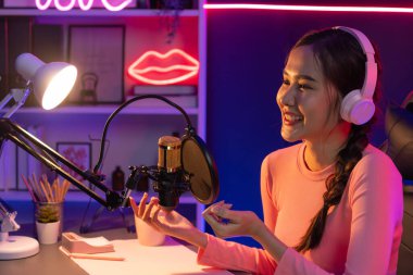 Geceleri podcast 'te olumlu konuşmalar yapan, pembe neon ışıklı modern stüdyoda sunum için dizüstü bilgisayar kullanan, gülümseyen, genç, güzel Asyalı bir etkileyiciydi. Taktik.