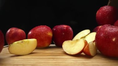 Makrografi, taze elma dilimleri çarpıcı bir siyah arka plana karşı bir kesme tahtasına yerleştirilmiştir. Her yakın çekim elmaların canlı dokusunu ve canlı renklerini yakalar. Geliştirilebilir.