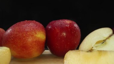 Makrografi, taze elma dilimleri çarpıcı bir siyah arka plana karşı bir kesme tahtasına yerleştirilmiştir. Her yakın çekim elmaların canlı dokusunu ve canlı renklerini yakalar. Geliştirilebilir.