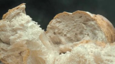 Koyu arkaplanda taze ekmek parçacıkları var. Tahta tepsiye yerleştirilmiş ekmeğin makro fotoğrafçılığı. Kamera hareketini yakınlaştır. Gurme ve fırın konsepti. Poster için tasarım, yemek blogu. Pabulum.