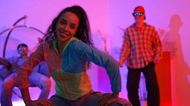 Çekici mutlu dansçı kameraya bakarken zeki kadın neon ışıkla kafiyeli hareket ediyor. Profesyonel İspanyol şarkıcı çeşitli arkadaşlarıyla renkli kıyafetler giyerken break dans yapıyor. Mutluluk.