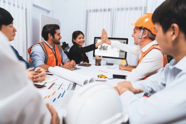 Çeşitli inşaat mühendisi ve müvekkil grupları, mimari proje üzerinde başarılı bir anlaşma yaptıktan, inşaat planını gözden geçirdikten ve toplantı masasında plan oluşturduktan sonra kutlama ve beşlik çakışma yaptılar.