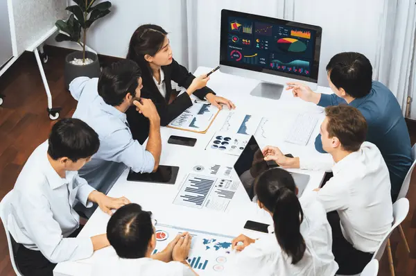 stock image Analyst team utilizing BI Fintech to analyze financial data at table in meeting room. Businesspeople analyzing BI dashboard power on paper for business insight and strategic marketing planning.Prudent