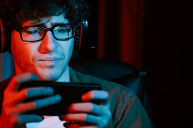 Stresli genç oyun flaması takımı akıllı telefondan Esport 'la oynuyor. Daha sert oyun seviyesinde, neon ışıklı odada kazanmanın utancı ve şaşkınlığı ile mücadele ediyorlar. Strateji planı uyguluyorum. Toplayıcı.