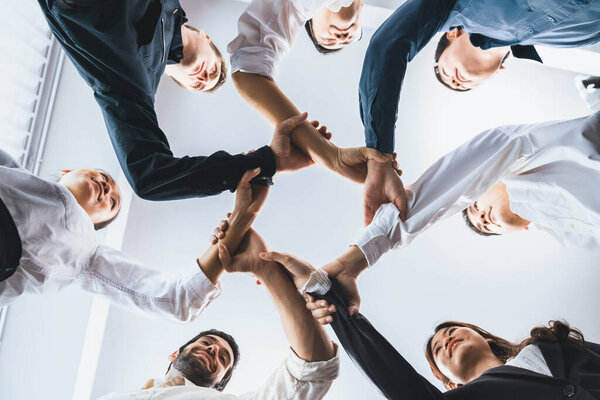 Business team joining hand in circular together symbolize successful group of business partnership and strong collective unity teamwork in diverse culture community workplace. Prudent