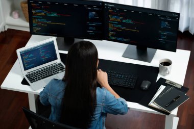 En iyi görünümlü genç Asyalı bilişim geliştiricisi web sitesi uygulamasının kodlama programı verileri ile bilgisayardan bilgi yazarak kot gömlek giyerek yaratıyor. Güvenlik analizi iki ekran ile çevrili. Taktik.