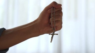 Hristiyan katolik takipçilerle dinsel bağlılık ve maneviyat duygusu doludur. Ağır çekimde el, güçlü bir kararlılıkla dini dua için kutsal haçı tutar. Filizlenen