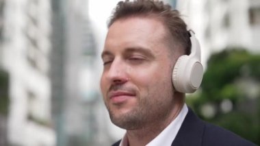 İş adamlarının kulaklıklarını kapat ve neşeli ve motive edici bir şekilde müzik eşliğinde dans et. Yetenekli proje yöneticisi şehir merkezinde bulanık arkaplanlı rahat şarkılar dinlemeyi sever. Urbane.