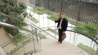 Kafkas işadamı akıllı telefon kullanarak müdürü arıyor ve mali raporları tartışıyor. Erkek lider, modern binada merdivenlerde dururken telefonla pazarlama ekibini konuşuyor. Urbane.