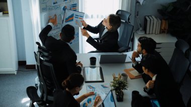 Akıllı yöneticinin üst görünümü, kurul ve kağıt arasındaki grafiği karşılaştırırken aynı zamanda başlangıç projesini iş toplantısında çeşitli takımlardan oluşan bir grupla birlikte planlıyor. Beyin fırtınası yapan ve birlikte çalışan takım. Müdürlük.