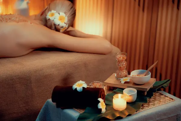 stock image Aromatherapy massage ambiance or spa salon composition setup with focus decor candles and spa accessories on blurred woman enjoying blissful aroma spa massage in resort or hotel background. Quiescent