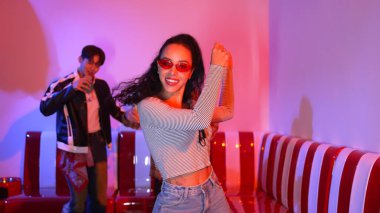 Çok kültürlü bir arkadaş birlikte dans ediyor ve hiphop müziği eşliğinde restoranda ya da kafede pembe neon ışıklı duruyor. Profesyonel sokak dansçıları grubu enerjik hareketler sergiliyor. Mutluluk.